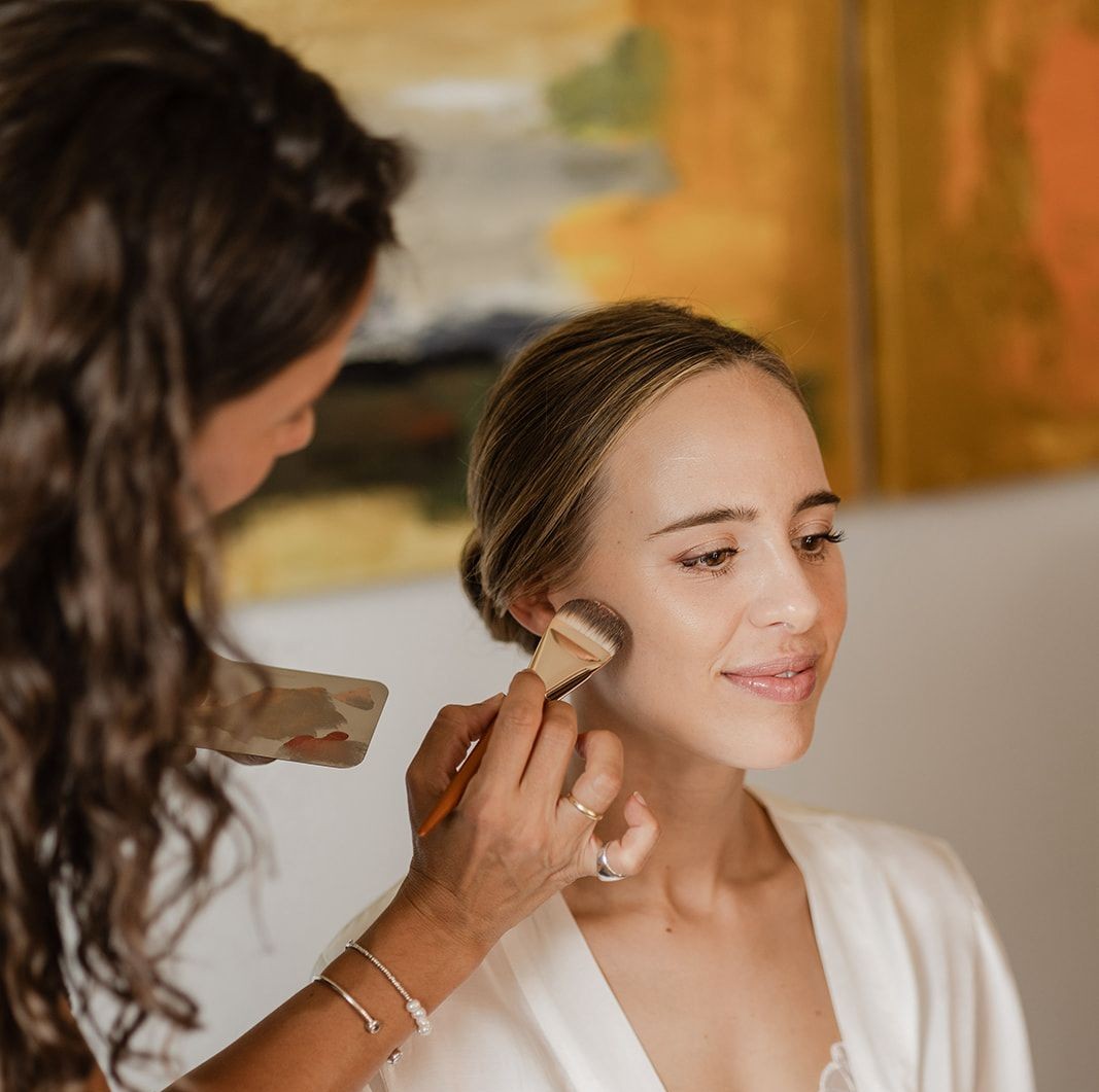 Isa Carrera aplicando colorete con brocha a una novia sonriente antes de la boda